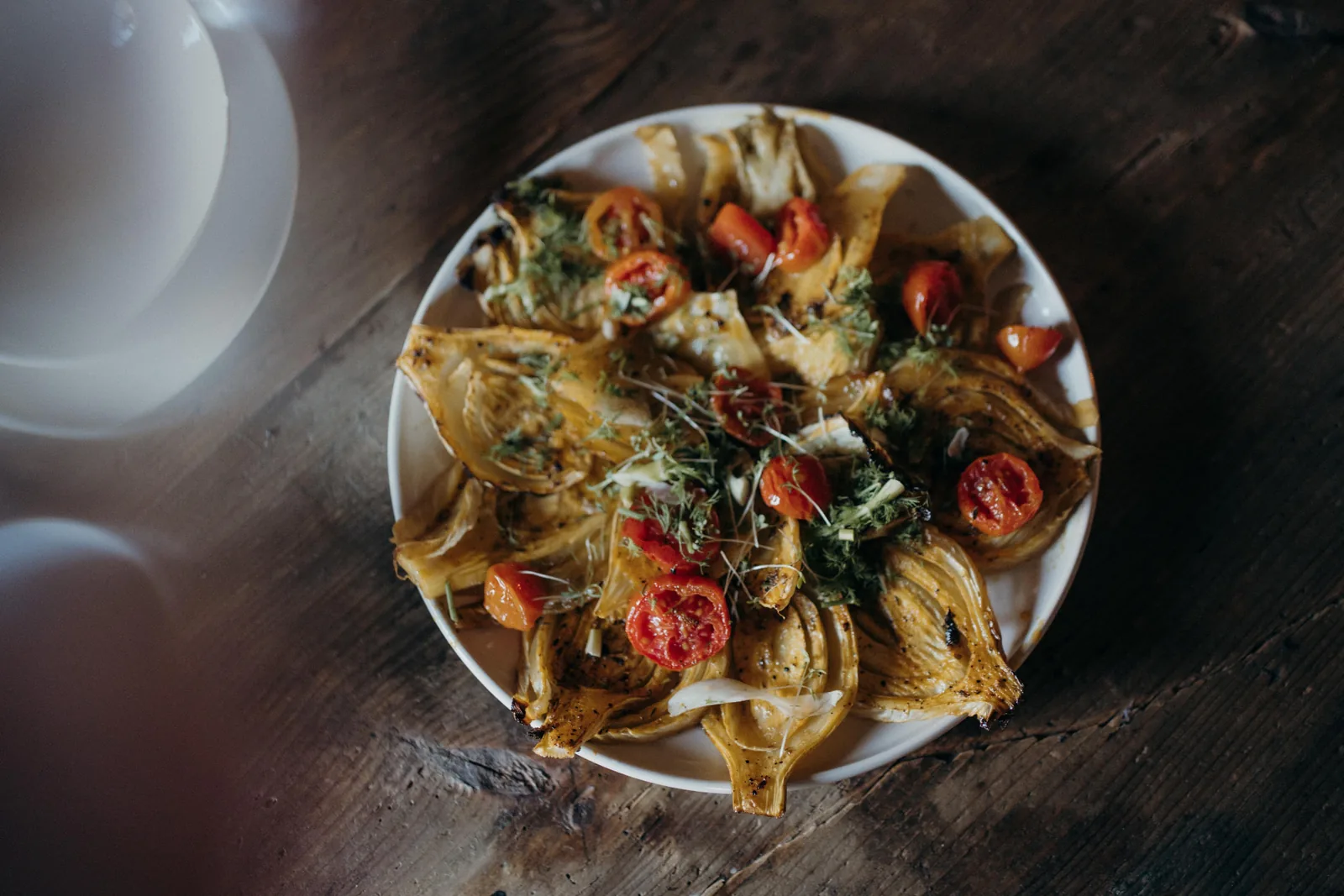 Gebratener Fenchel mit Kirschtomaten und Kräutern auf einem Teller